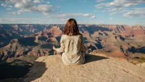 woman meditating on cliff edge